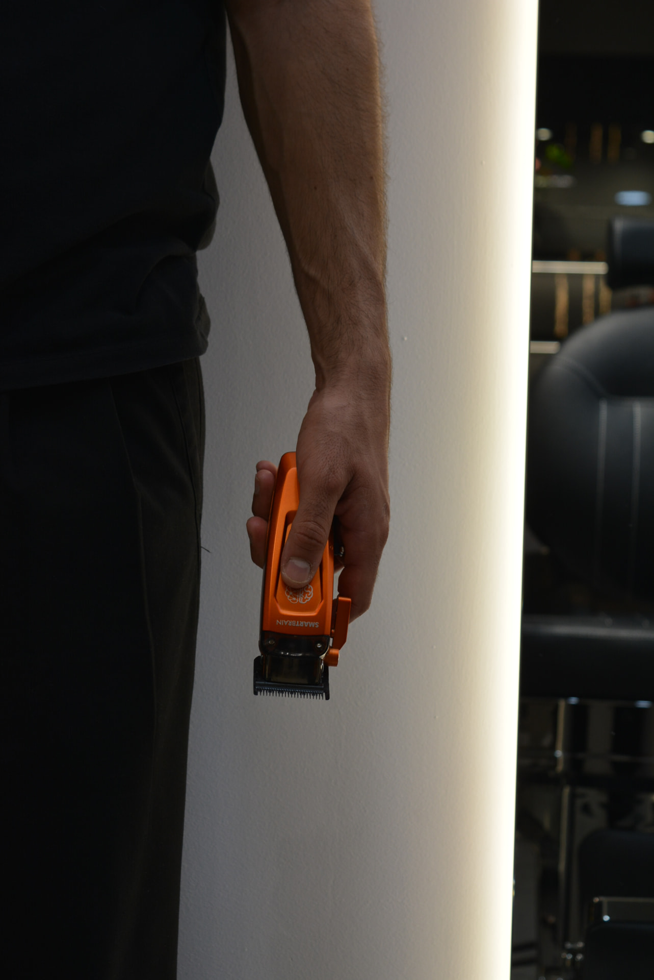 Barber holding an orange clipper at Primera Barbershop