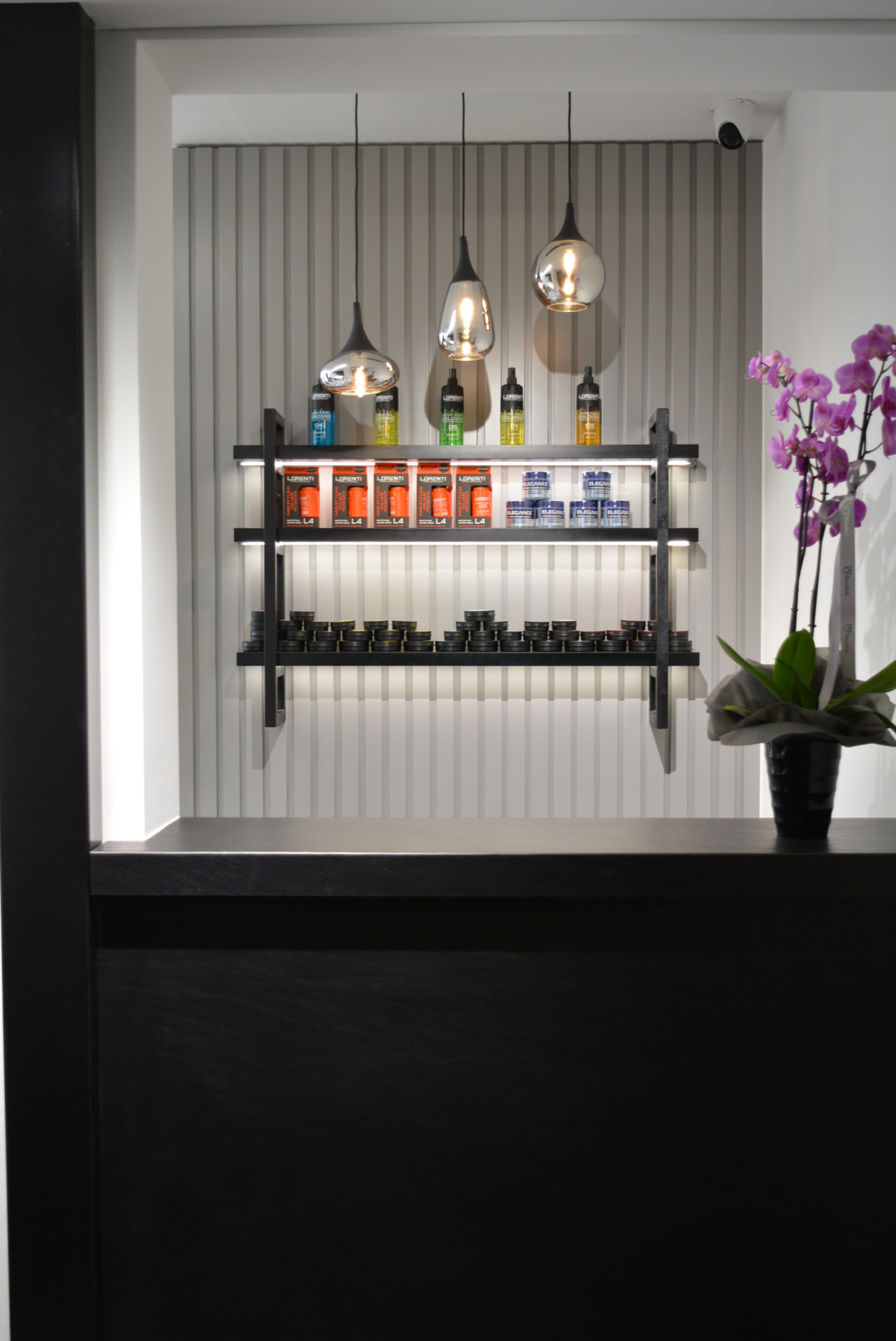 The reception shelf with pendant lights at Primera Barbershop