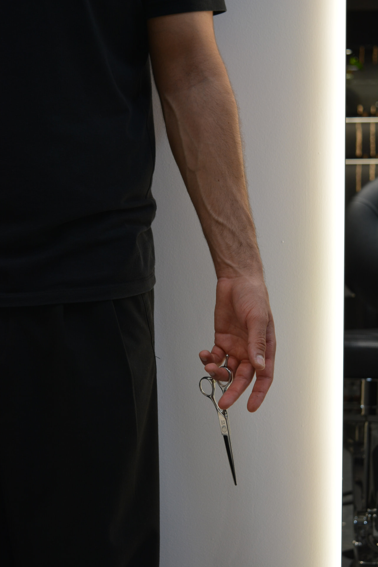 Barber holding scissors at Primera Barbershop