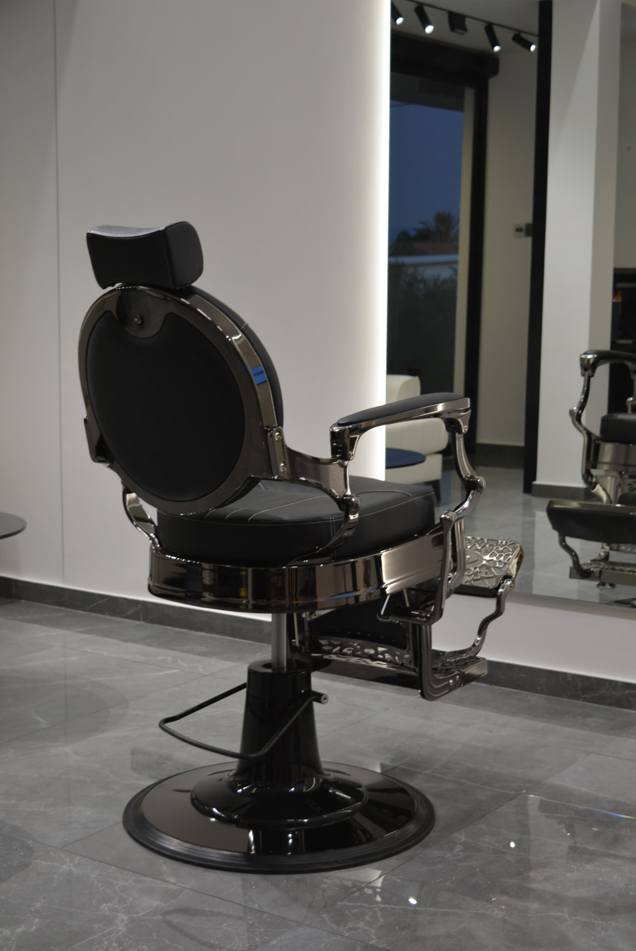 Glossy black barber chair at Primera Barbershop